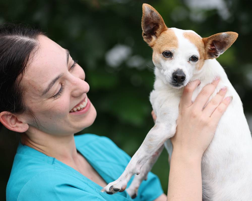 Smiling woman holding small dog.