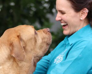 BVRS team member laughing while sharing a moment with a Labrador