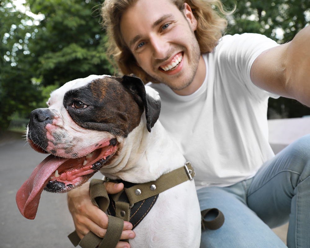man smiling taking selfie with his boxer dog